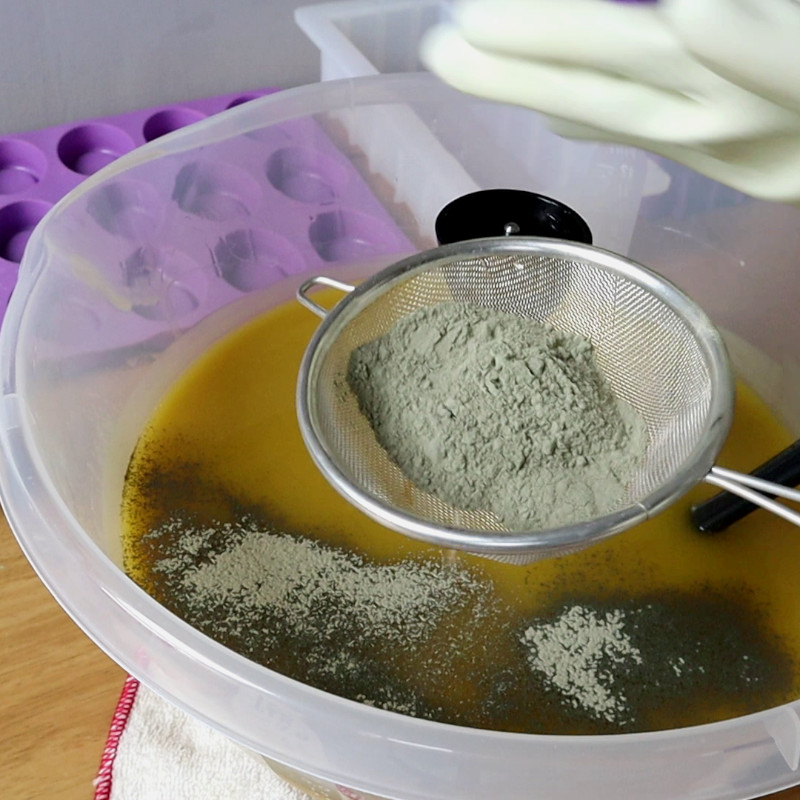 sieving french green clay onto soap batter