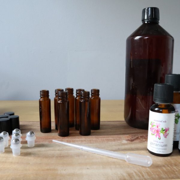essential oil roll-on making station with glass bottle, stainless steel roller ball, lid, pipette, essential oil and sweet almond oil bottle