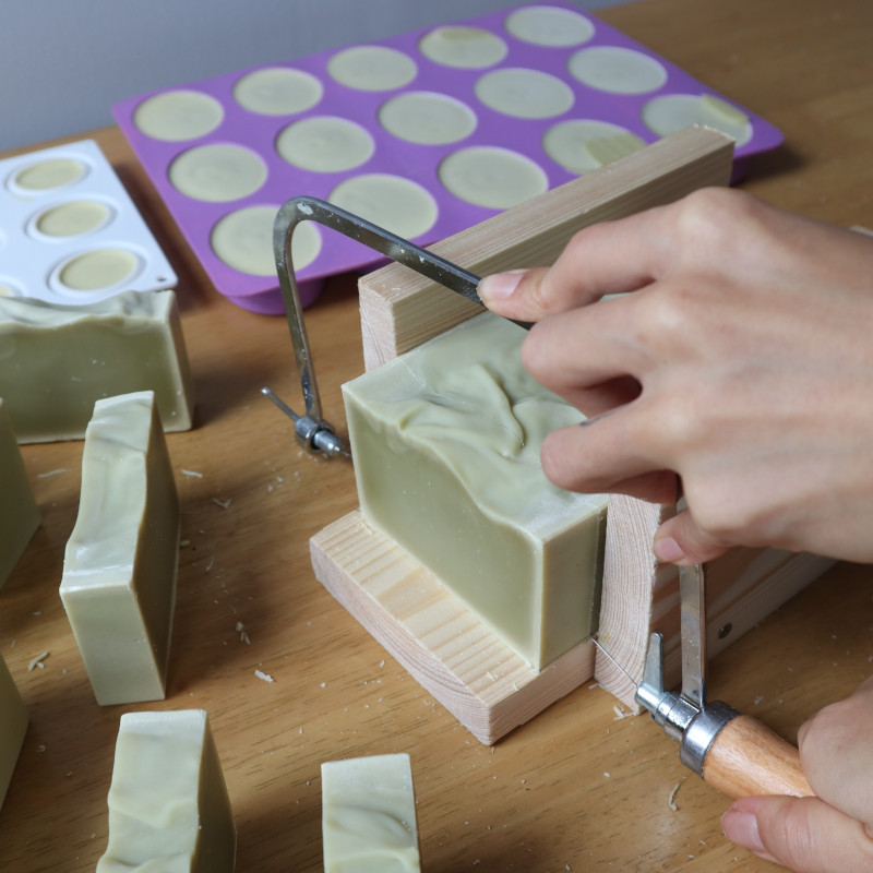 hand cutting loaf of soap with wire cutter