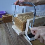 cutting rustic turmeric soap loaf with wire cutter